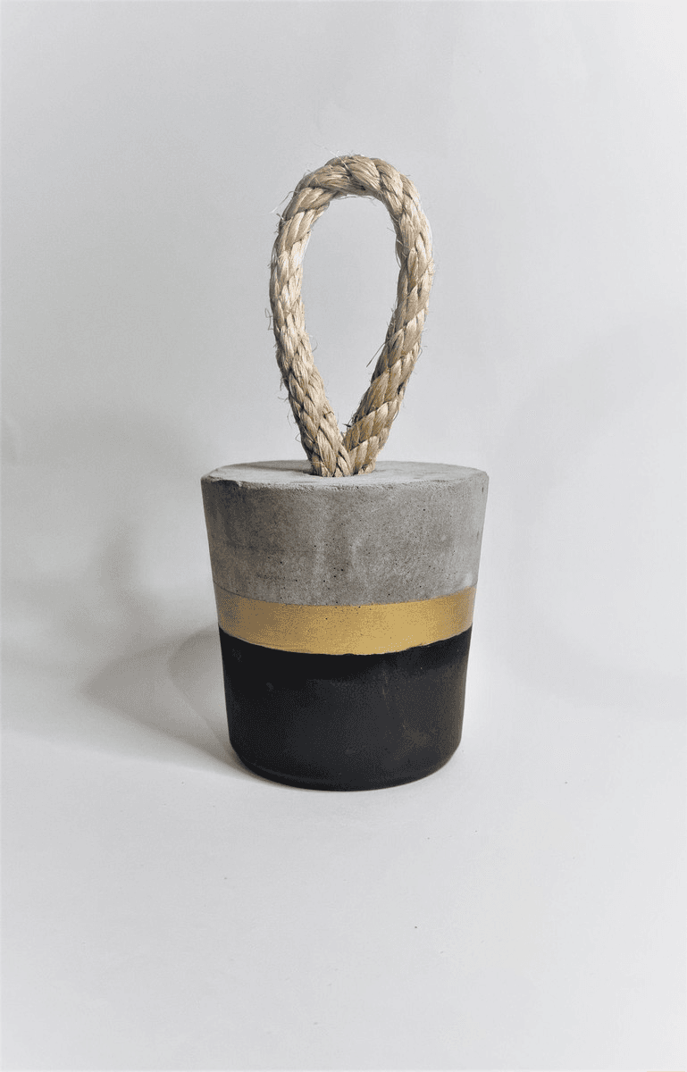 Imagem de um peso de porta de concreto com uma faixa preta e outra dourada