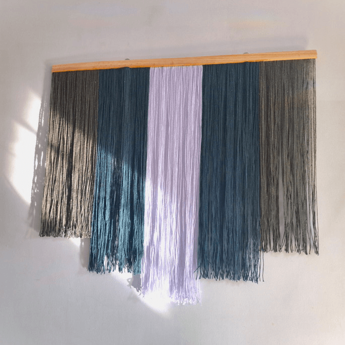 Imagem de um painel de macramê branco, verde musgo e verde escuro