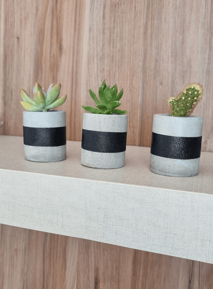 Imagem de 3 vasinhos de cimento com uma faixa na cor preta