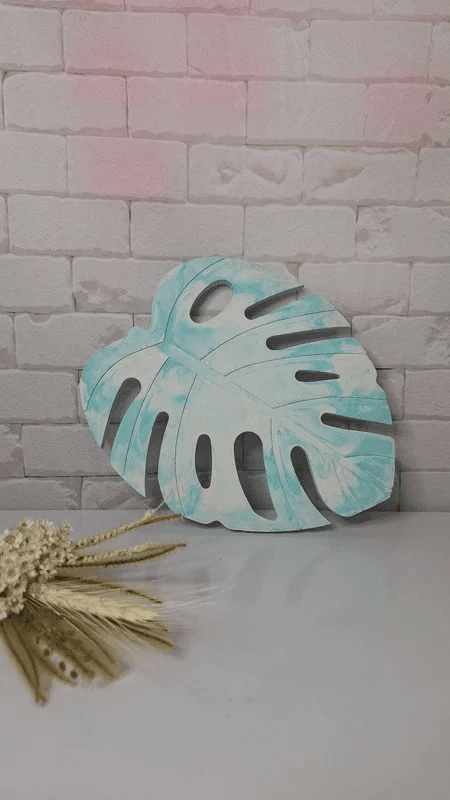 Imagem de uma bandeja de concreto no formato de uma folha com pintura marmorizada verde e branca